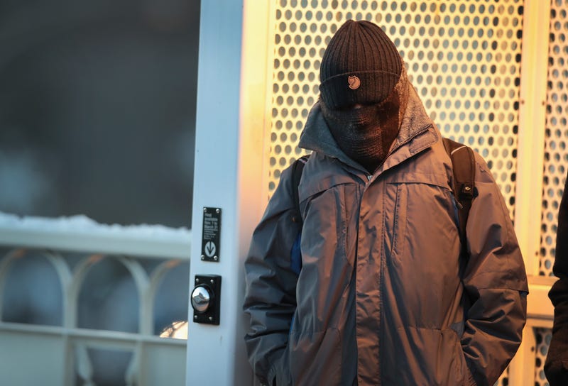 A commuter, bundled for warmth, waits for a train