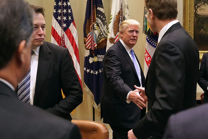 U.S. President Donald Trump (C) greets Wendell Weeks (R) of Corning, Elon Musk of SpaceX (L) and other other business leaders as he arrives for a meeting in the Roosevelt Room at the White House January 23, 2017 in Washington, DC