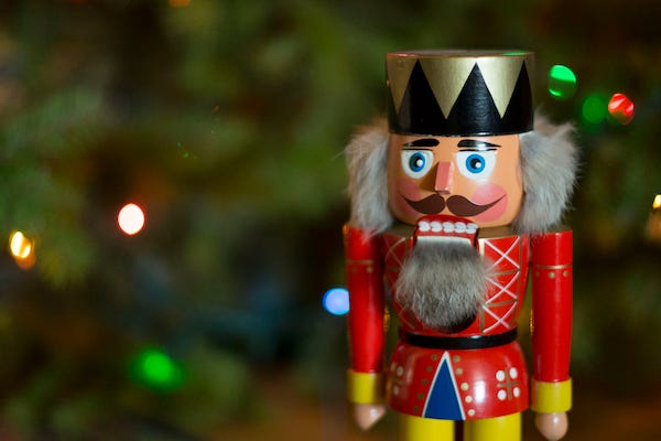 Nutcracker standing in front of a Christmas tree