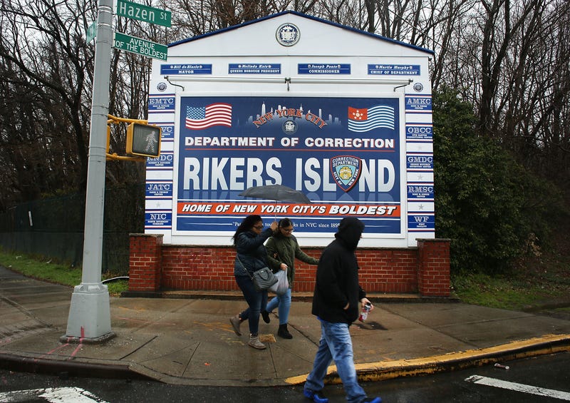 People walk by a sign at the entrance to Rikers Island on March 31, 2017 in New York City.
