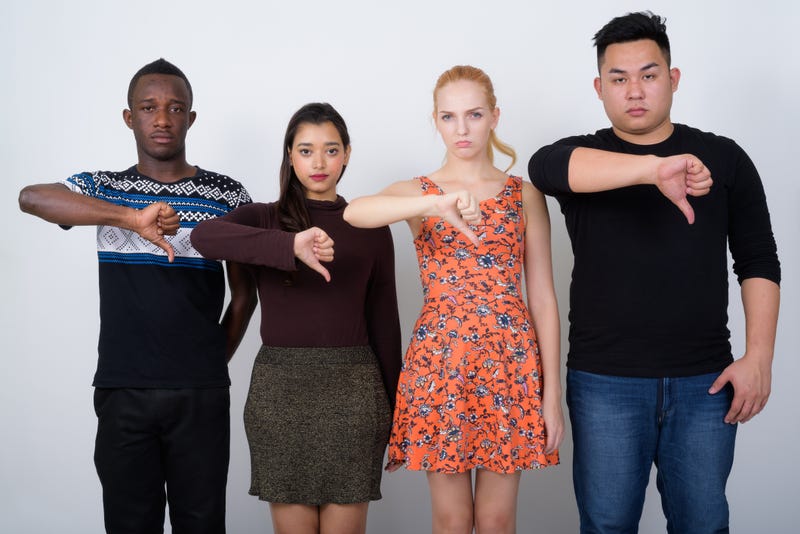 Composition of group of friends over blue blackground looking unhappy and angry showing rejection and negative with thumbs down gesture. Bad expression.