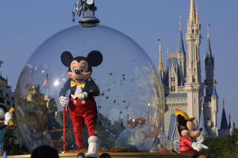 mickey mouse in a glass globe in front of disney castle