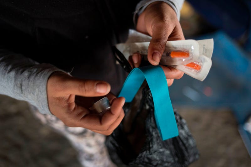 Homeless heroin user shows her kit of clean needles, mixing cap and tourniquet in Kensington