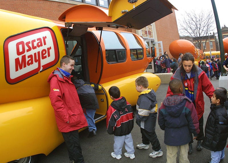 Students line up for a tour of an Oscar Mayer Wienermobile January 23, 2002 at Oscar Mayer Elementary School in Chicago. Oscar Mayer kicked off a national classroom vocal contest at Chicagos Oscar Mayer Elementary School to recognize and encourage performing arts in Education. The school was presented $10,000 worth of musical equipment and tours of one of four Wienermobiles parked in the schools playground as a thank you from Oscar Mayer for helping to support the kick-off of the School House Jam talent search contest. (Photo by Tim Boyle/Getty Images)