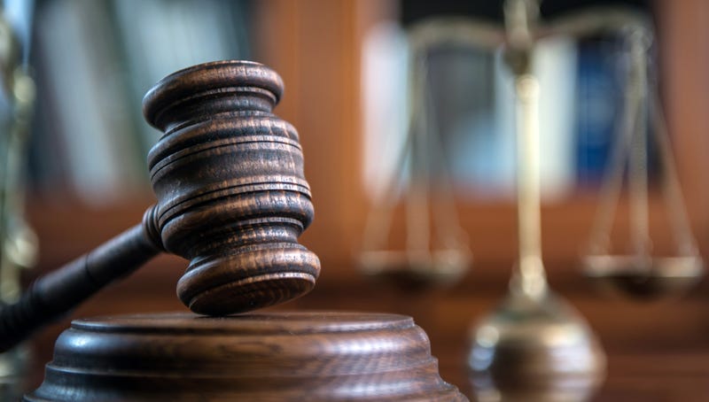 A judge's gavel, with a scale in the background
