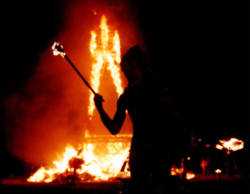 Dancer juggles fire as a 52-foot tall wooden man as it goes up in flames September 2, 2000 during the15th annual Burning Man festival in the Black Rock Desert near Gerlach, Nevada. 