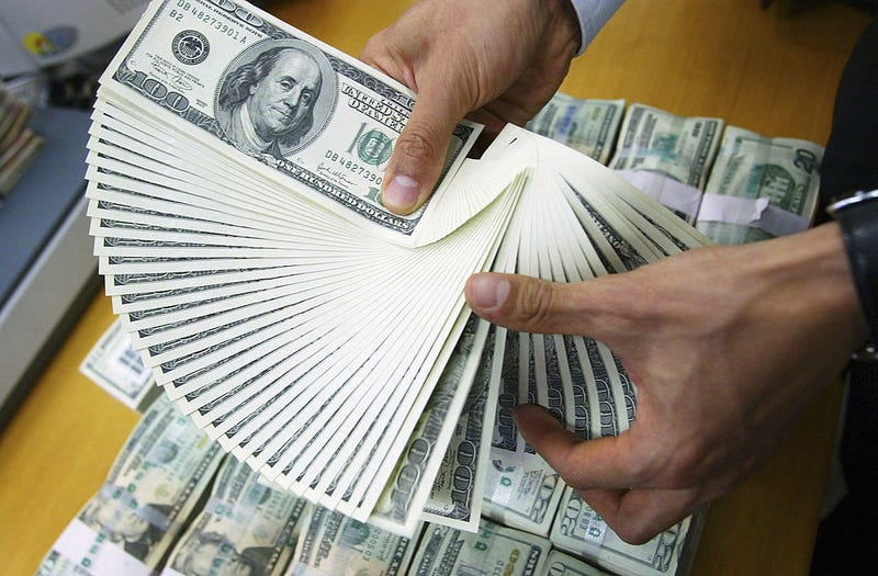 A man's hands holding lots of $100 bills