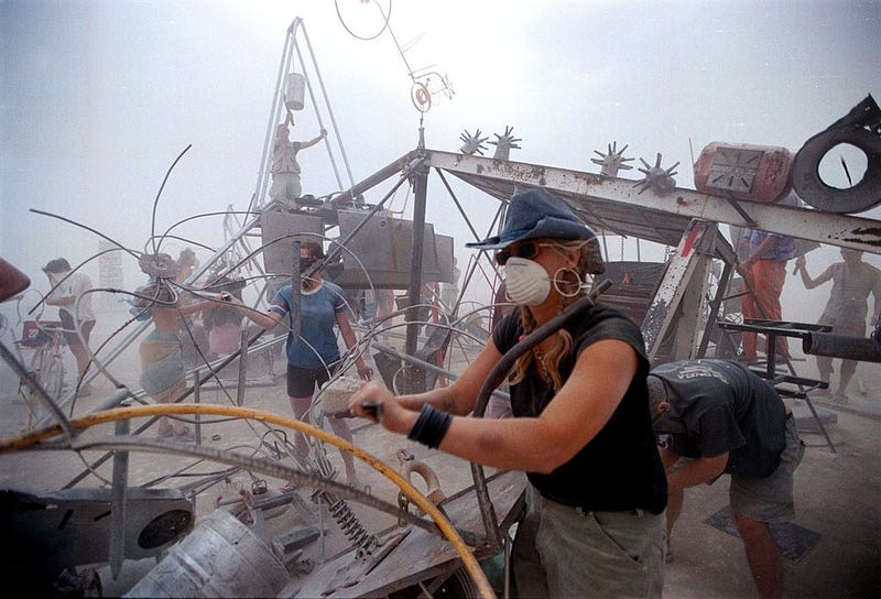 People drum on a percussion junk pile despite a blinding dust storm caused by strong winds September 2, 2000 at the 15th annual Burning Man festival in the Black Rock Desert near Gerlach, Nevada. 