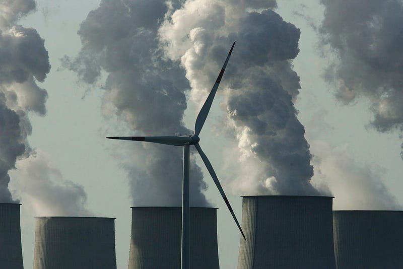 A loan wind turbine spins as exhaust plumes from cooling towers at the Jaenschwalde lignite coal-fired power station, which is owned by Vatenfall, April 12, 2007 at Jaenschwalde, Germany. 