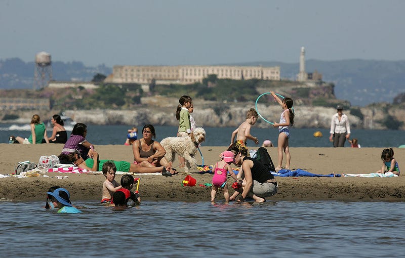 Alcatraz Island sits in the background as people play on the beach at Crissy Field May 7, 2007 in San Francisco, California.