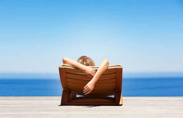 Woman reclining on beach chair in front of water