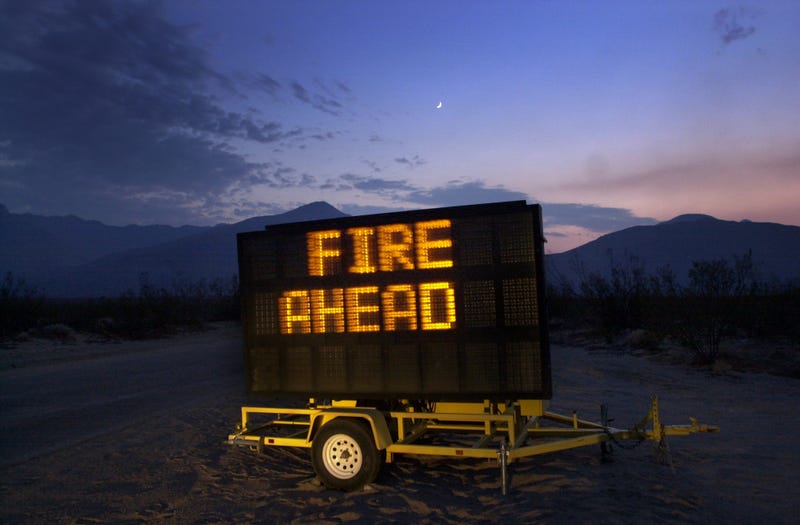 Sign warns of a wildfire in the distance