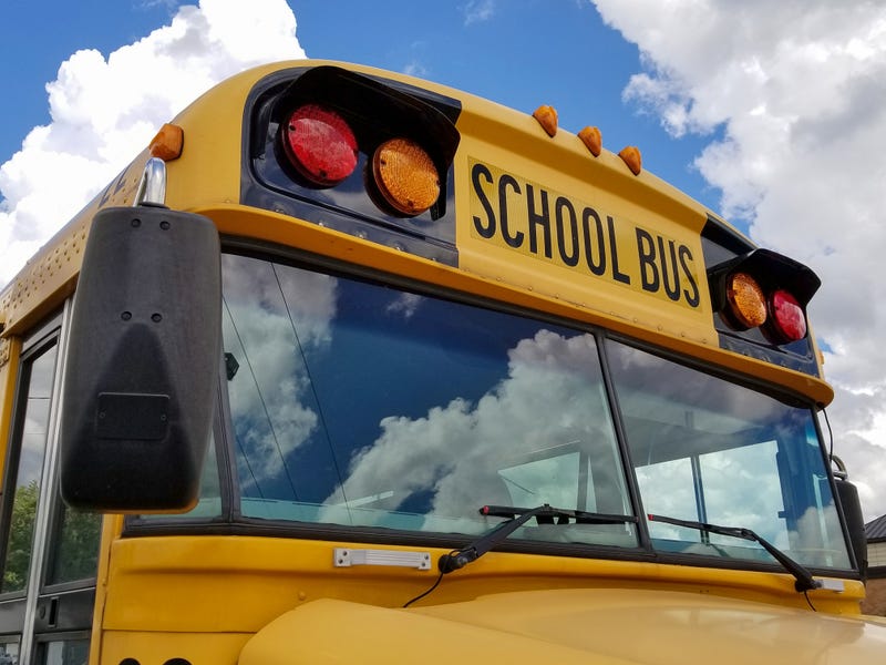 front view of yellow school bus with cloud reflection in windshield