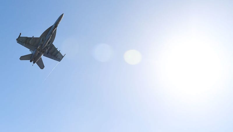 A US Navy Super Hornet flies over the deck of the USS Ronald Reagan.