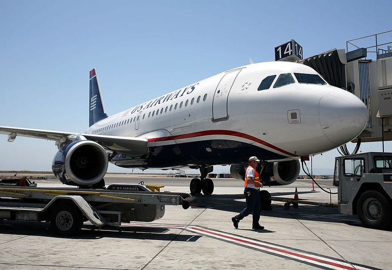 A worker walks by a U.S. Airways plane parked at the gate at the Oakland International Airport July 18, 2008 in Oakland, California.