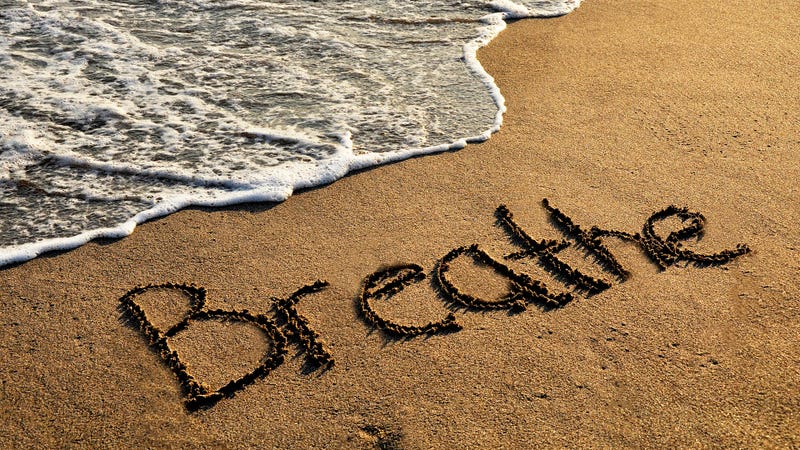 "Breathe" written in sand on a beach