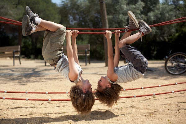 Kids hanging upside down while playing at a park