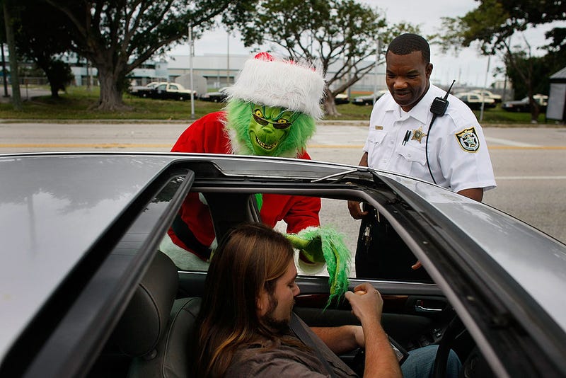 Monroe County Sheriff's Colonel Lou Caputo, dressed as the Grinch, and Monroe County Sheriff deputy James Jenkins warn a driver that he was driving too fast through a school zone December 19, 2008, in Marathon, Florida. Lieutenant Caputo wears the Grinch custom as part of a campaign to bring attention to the fact that people need to drive carefully, follow the posted speed limit and wear their seatbelts. (Photo by Joe Raedle/Getty Images)