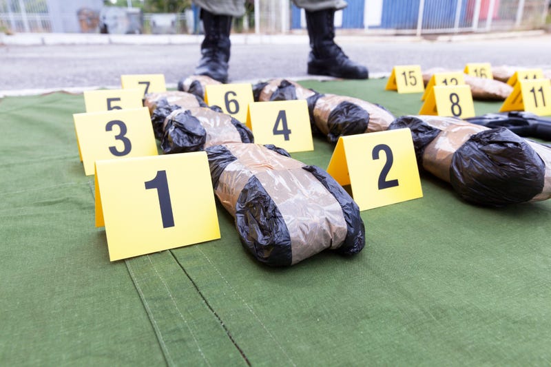 Drug seized during the police raid - stock photo Police officer standing guard over seized packages of drug