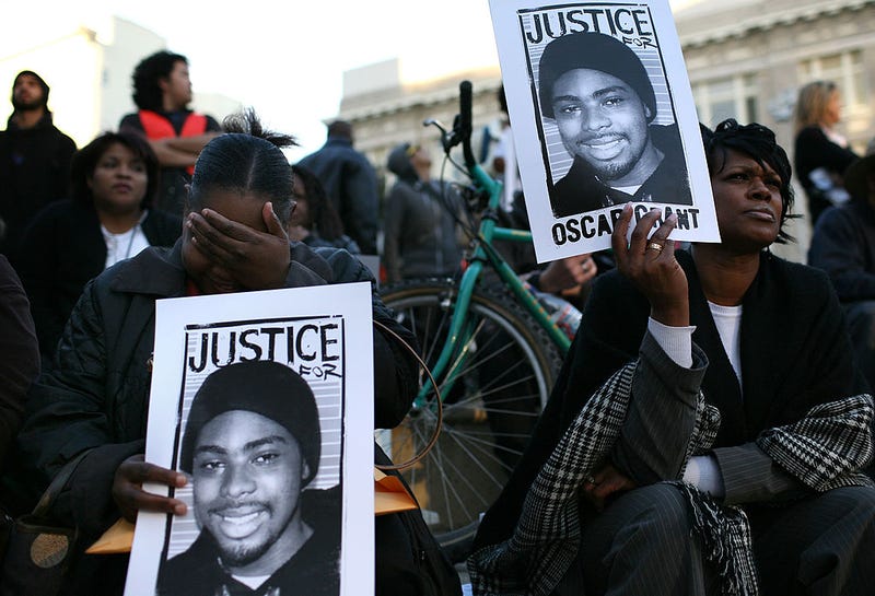 Protestors carry signs with a picture of slain 22-year-old Oscar Grant III during a demonstration at Oakland City Hall January 14, 2009 in Oakland, California.