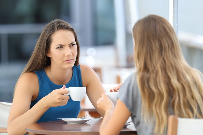 Two serious friends having a conversation sitting in a bar terrace