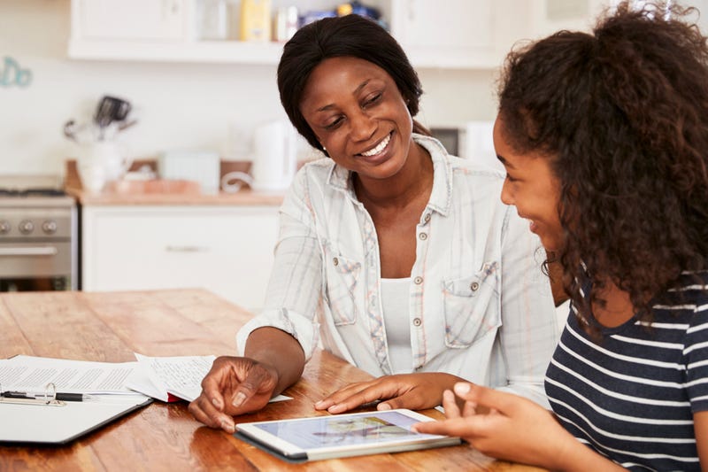 A mother and daughter complete a digital school assignment on a tablet