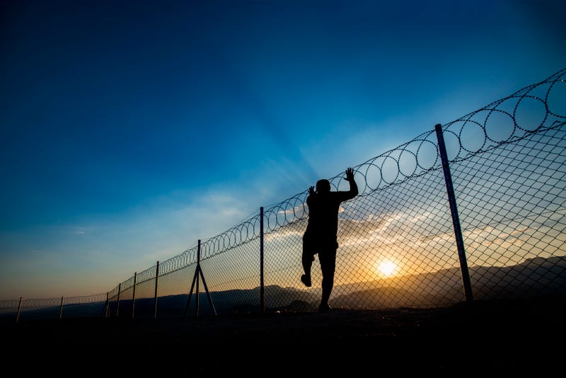 An inmate climbs a prison's wire fence in an attempt to escape