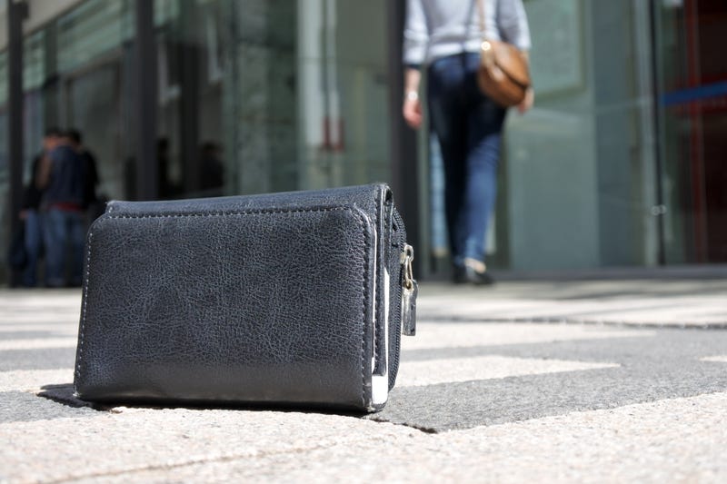 Woman walking away after losing her wallet on city street. loss concept. Real people. Copy space
