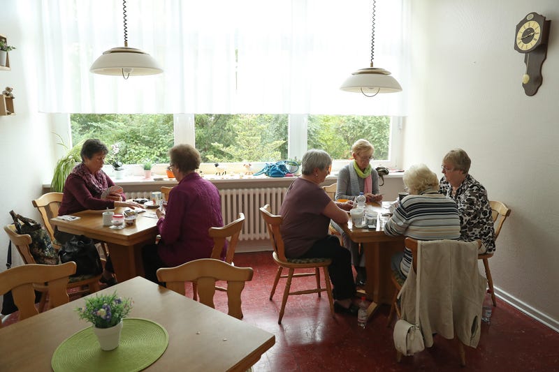A group of elderly women play card games at a senior citizen facility.