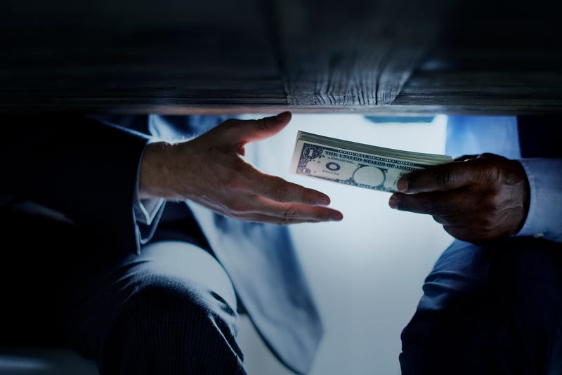 hands exchanging money under table