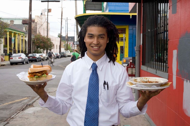 Waiter holding a plate with a poboy on it