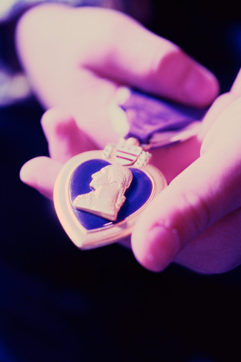 A Purple Heart medal in a person's hands