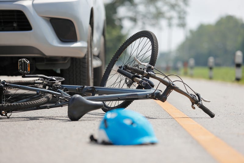 bicycle lying on road in front of car
