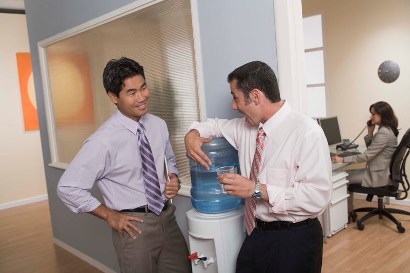 Men standing at water cooler in office