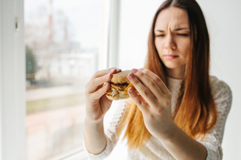 A young girl shows that she does not like a burger.Conceptual image of refusal from unhealthy eating. Fast food.