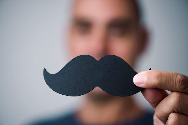 Man holding up a fake mustache