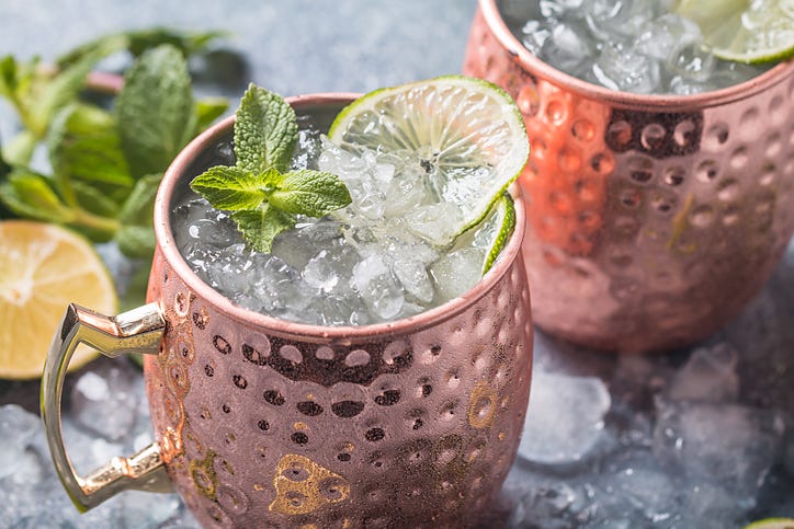Moscow mule cocktail in copper cup with lime, ginger beer, vodka and mint garnish