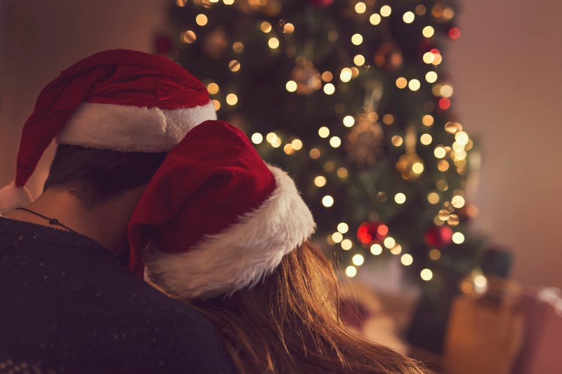 Couple sitting next to a Christmas tree