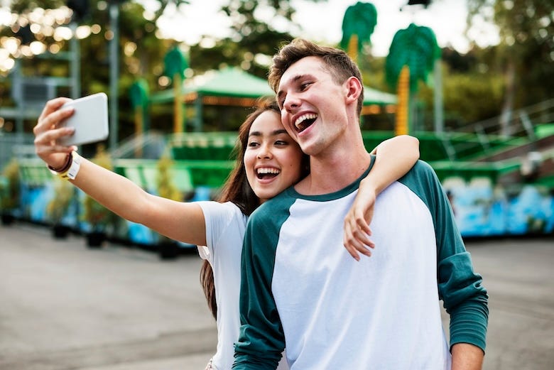 Teens posing for a selfie at an amusement park