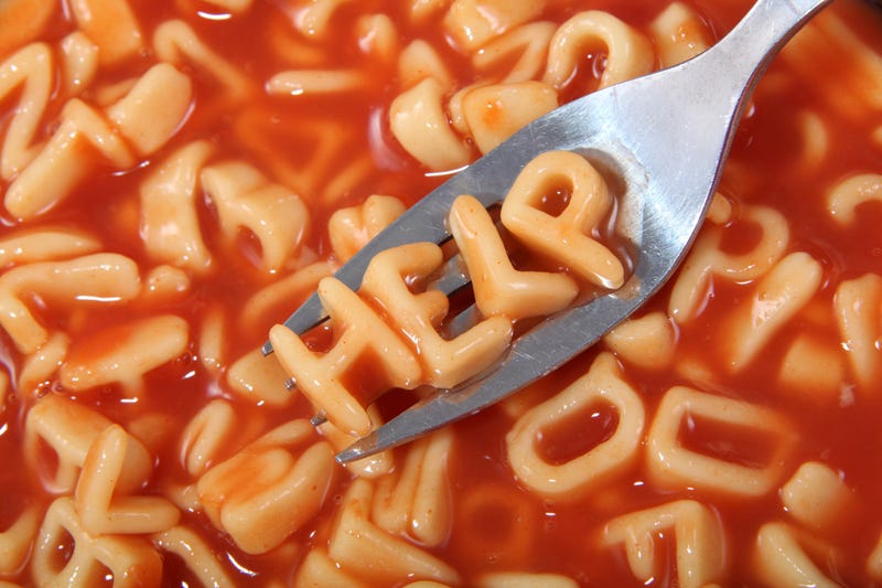 Canned spaghetti noodles spelling out the word "help" on a utensil.
