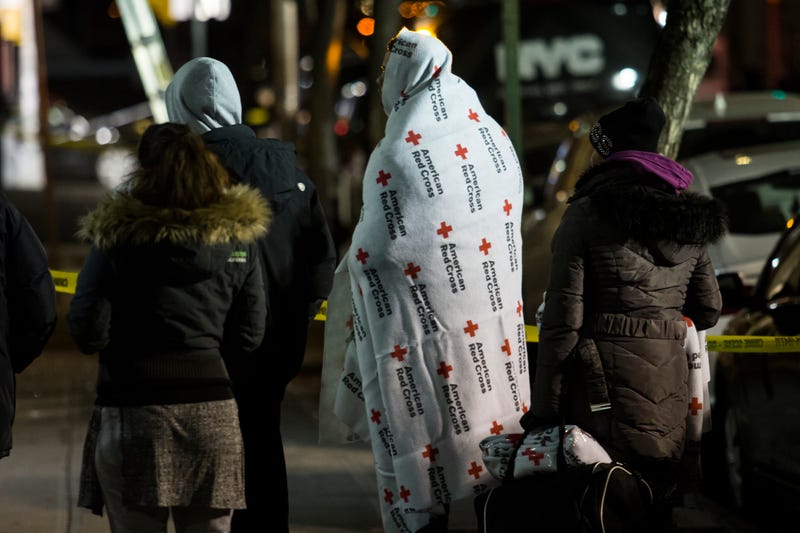 People who evacuate from their house after a fatal major house fire on Prospect avenue on December 29, 2017 in the Bronx borough of New York City. Over 170 firefighters respond to the evening fire in which at least 12 persons were killed with others injured.