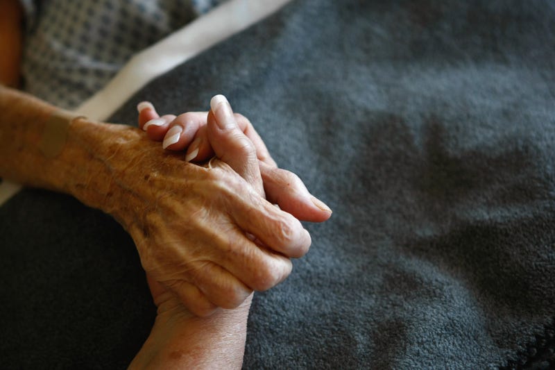 A terminally-ill hospice resident is comforted in her bed.