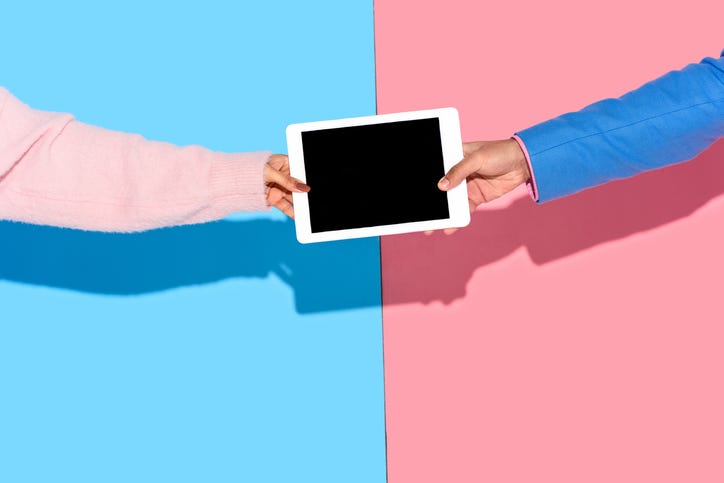 Hands holding digital tablet on pink and blue background