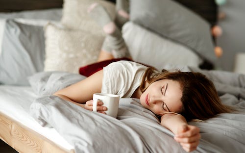 Woman with coffee laying in bed
