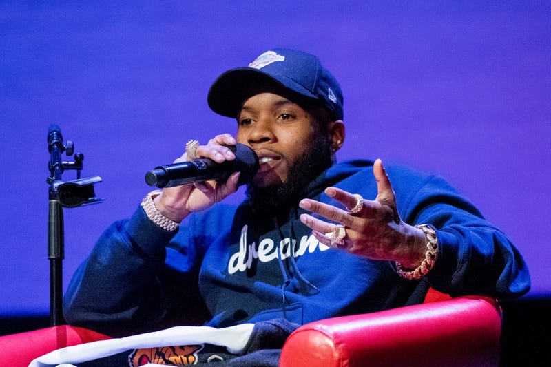 tory lanez speaks into mic sitting onstage