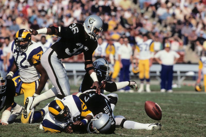 Mike Davis #36 of the Los Angeles Raiders chases after a fumble caused by teammate Lyle Alzedo #77 on running back Wedell Tyler #26 of the Los Angeles Rams during the game at the Los Angeles Memorial Coliseum on December 18, 1982