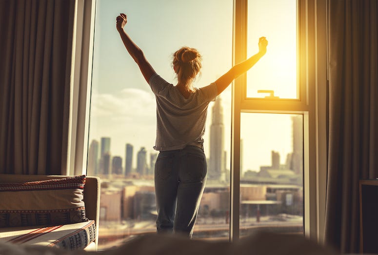 Woman stretches waking up looking out window
