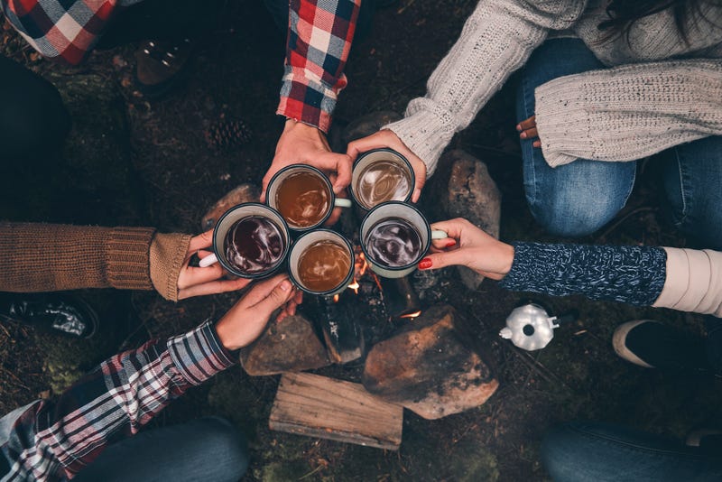 Friends toasting each other while warming up near the campfire