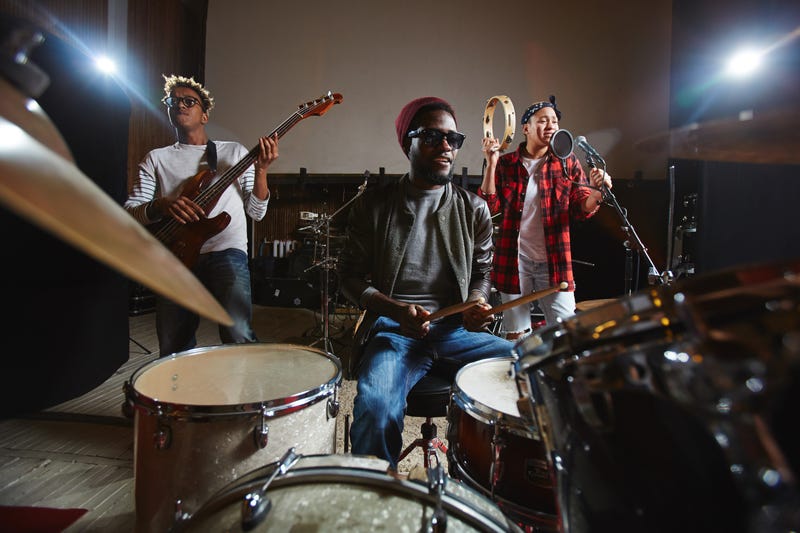 Three young musicians playing musical instruments and performing songs in studio of records
