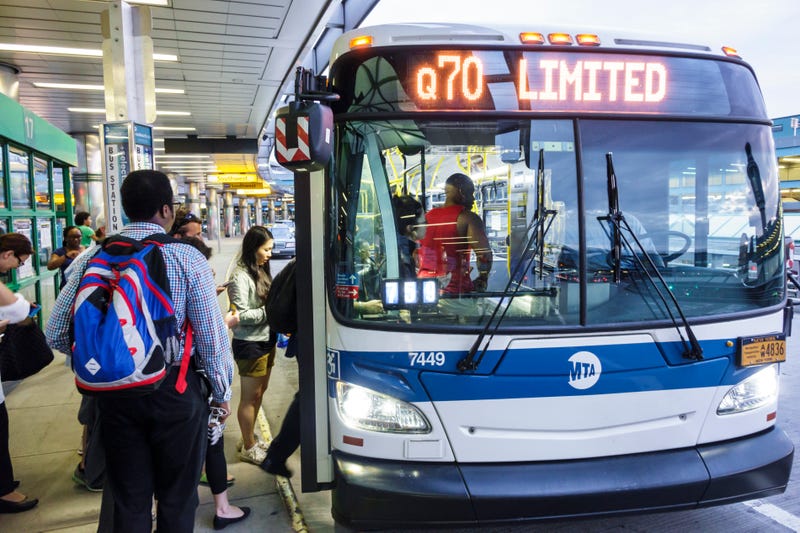 Men and women boarding a Q70 Limited bus outside LaGuardia Airport.